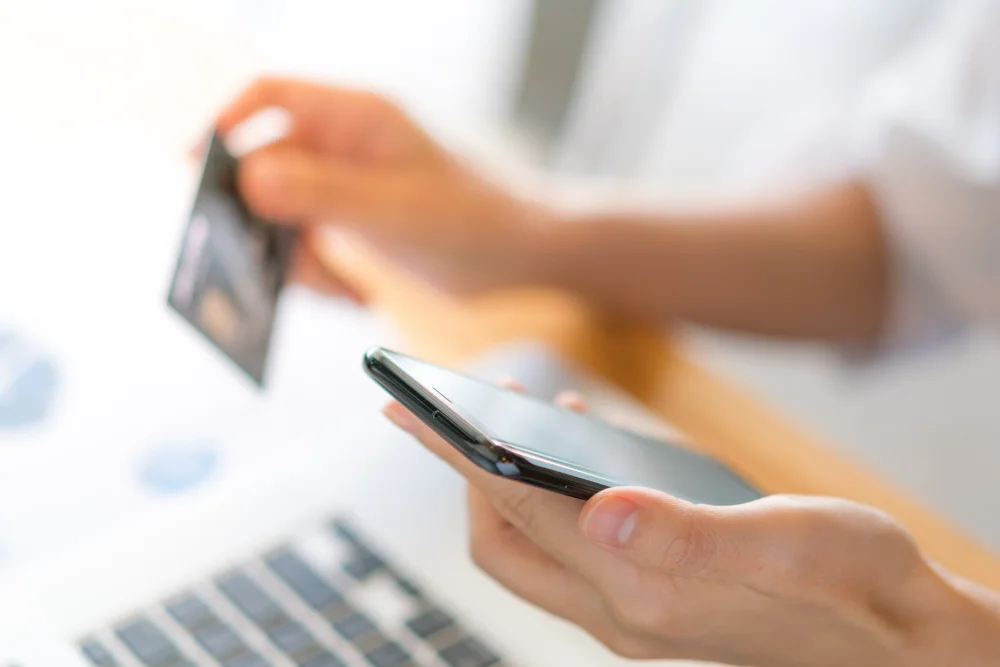 Persona usando el móvil y una tarjeta bancaria para realizar un pago digital de forma segura