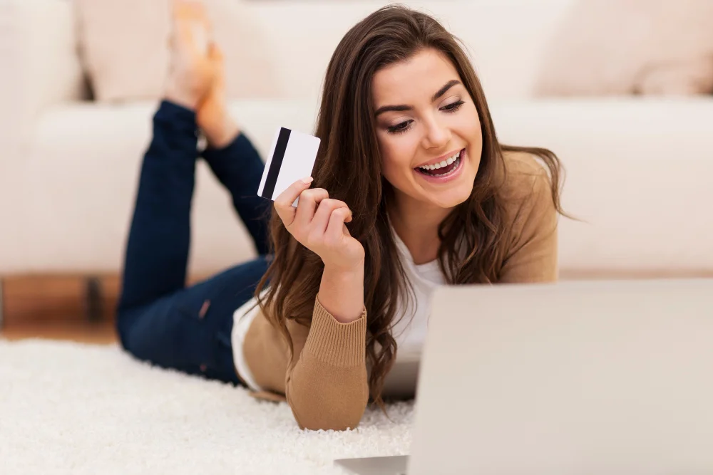 Mujer revisando su tarjeta frente al portátil antes de enviar dinero online